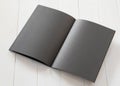 Blank A4 size black book template mock up with open double page placing on white wood table Royalty Free Stock Photo