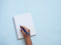 Blank spiral notebook with caucasian hand holding a blue pen ready to write. Royalty Free Stock Photo