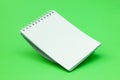Blank spiral notebook falling on the green background Royalty Free Stock Photo
