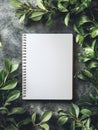Blank spiral notebook surrounded by green foliage on a textured surface for creative expression and inspiration Royalty Free Stock Photo