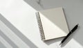 Blank Spiral Notepad with Black Pen on White Marble Table in Bright Light Royalty Free Stock Photo