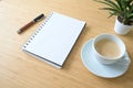 Blank spiral notepad, coffee cup, pen and a plant on a desk made of bamboo wood, business or home office concept, mockup, copy Royalty Free Stock Photo