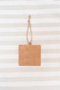 Blank square label, brown paper tag lies on bed linen. Craft cardboard tag. Copy space. Place for text and company logo