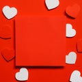 Blank square paper on red backdrop, red and white paper cut in the shape of a little heart on red background, greetings card ideas