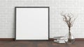 Blank square poster frame mock up standing on dark parquet floor next to white brick wall with vase and books. Clipping path aroun