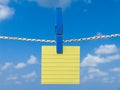 Blank square of yellow paper suspended from a washing line.