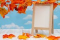 Blank standing whiteboard on weathered wood with fall leaves Royalty Free Stock Photo
