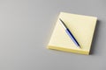 Blank sticky paper notepad and pen on gray table Royalty Free Stock Photo