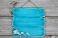 Blank teal blue sign with seashells hanging on rustic wooden door