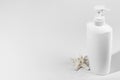 Blank unbranded bottle with dispenser and starfish on light shadow backdrop, copy space. Mockup style. White container for