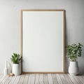 Blank vertical poster frame leaning on white wall with decorative plants on wooden floor, minimalist interior design Royalty Free Stock Photo