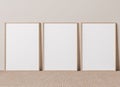 Blank vertical poster frame mock up standing on beige floor.