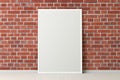 Blank vertical poster frame mock up standing on white floor next to red brick wall. Royalty Free Stock Photo