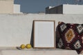 Blank vertical wooden frame picture mock up. Fresh lemon fruit, Mexican pattern cushion. White old textured white wall