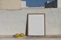 Blank vertical wooden frame picture mock up with fresh lemons fruit. White old textured white wall in sunlight. Summer Royalty Free Stock Photo