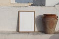 Blank vertical wooden frame picture mock up with vintage olive clay storage pot, vase. White old textured white wall in Royalty Free Stock Photo