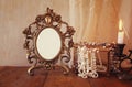 Blank vintage frame, pearls and burning candle