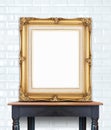 Blank vintage golden photo frame lean at ceramic tile wall on wood table Royalty Free Stock Photo