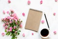 Blank vintage paper notebook in frame made of pink rose flowers with coffee cup over white marble table Royalty Free Stock Photo