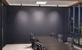 Blank wall Mockup in dark modern office with windows and spotlights. Empty company meeting room 3D rendering Royalty Free Stock Photo