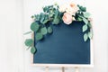 Blank wedding chalkboard sign mockup scene. Floral garland of green eucalyptus branches and apricot English roses