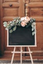 Blank wedding chalkboard sign mockup scene. Wooden easel with welcome board. Floral garland of green eucalyptus branches Royalty Free Stock Photo