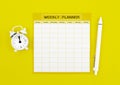 The Blank weekly plan notice block with alarm clock with yellow background. Empty schedule