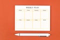 The Blank weekly plan notice block on orange colour background. Empty schedule and a pen