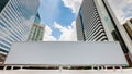 Blank white advertising billboard with modern city business center buildings in background with blue sky