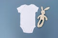 Blank white baby bodysuit grow mockup with cream rabbit soft toy on a light blue background Royalty Free Stock Photo
