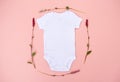 Blank white babygrow bodysuit surrounded by delicate pretty pink flowers