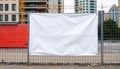 A blank white banner hangs on a construction site fence. The background features a red construction container and modern Royalty Free Stock Photo