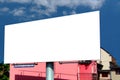 Blank white billboard ad panel in urban residential setting with clear blue sky and pink facade Royalty Free Stock Photo