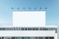 Blank white billboard with spotlights on top of industrial building on blue sky background. 3D rendering, mockup Royalty Free Stock Photo