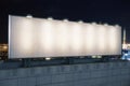 Blank white billboard on the top of building at night city background, mock up Royalty Free Stock Photo