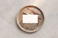 Blank white business card mockup on wooden plate. Marble backgound with dry colorful eucalyptus leaves. Modern template