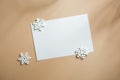 Blank white business greeting card mockup and snowflakes. on beige table backgound