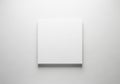 A blank white canvas is centered on a light gray textured wall. The canvas is square and unadorned, Royalty Free Stock Photo