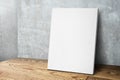 Blank white canvas frame leaning at concrete wall and wood floor Royalty Free Stock Photo