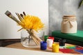 Blank white canvas, yellow chrysanthemum and different painting tools on wooden table