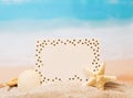 Blank white card, starfish and shell in sand against sea. Royalty Free Stock Photo