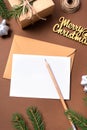 Blank white Christmas card template on beige background. Fir branches, holiday decorations