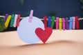 Blank white circle paper with red heart and colorful wooden paper clips on rope.