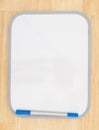 Blank white dry erase board with marker on wood textured background