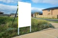 Blank white empty mockup template of a real estate sign at front of a lot of vacant land in a suburban neighbourhood Royalty Free Stock Photo