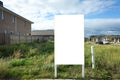 Blank white empty mockup template of a real estate sign at front of a lot of vacant land on a suburban neighbourhood street