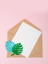 Blank white envelope on paper monstera sheet on pink background