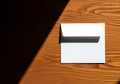 Blank white envelope on a wooden surface with dramatic sunlight Royalty Free Stock Photo