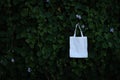 Blank white fabric cloth bag tote at green bush trees foliage Background Royalty Free Stock Photo