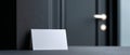 Blank white folded card placed on dark textured surface near closed door with metallic handle in modern interior setting Royalty Free Stock Photo